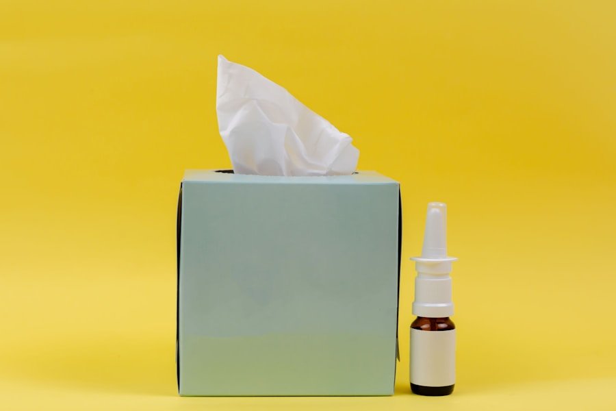 A tissue box and a nasal spray bottle are placed against a yellow background.